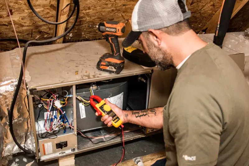 Moore's A/C & Heating technician working on a heater