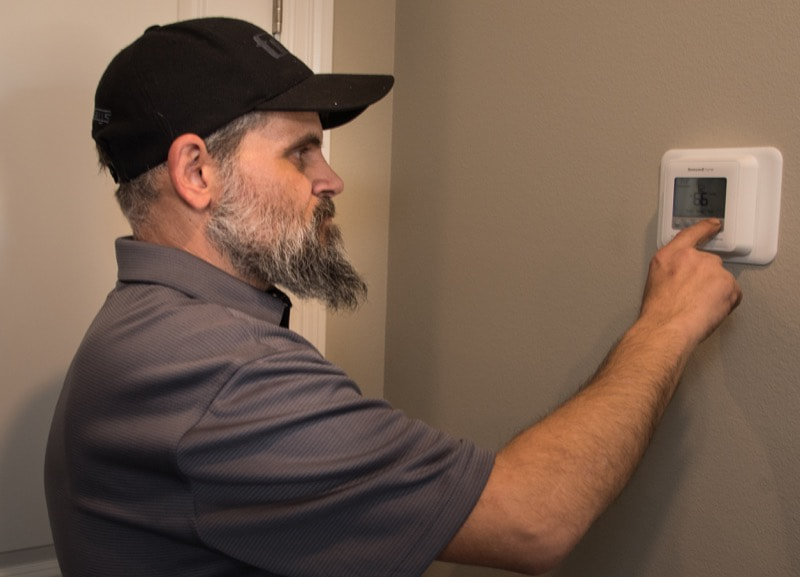 Checking the thermostat at Moore's A/C & Heating Inc. 